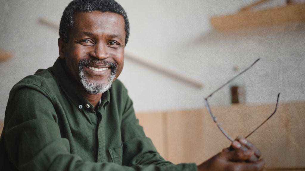 Man with beard holding eye glasses and smiling