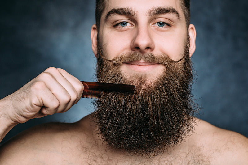 man combing his thick beard
