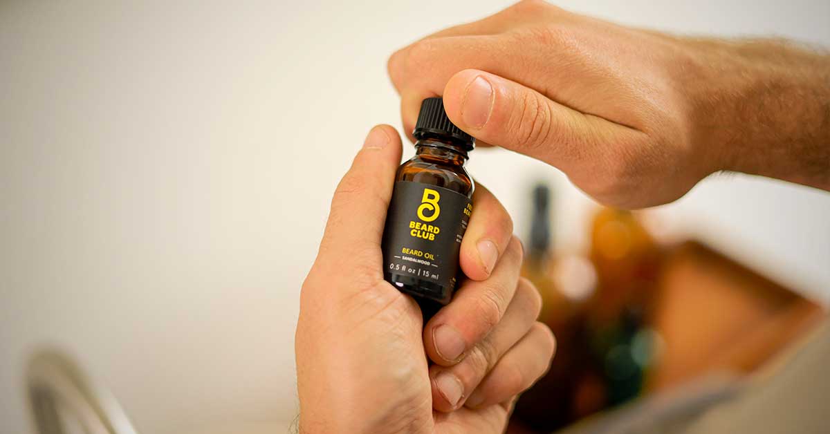 Barber applies beard oil with dropper for man in barbarshop