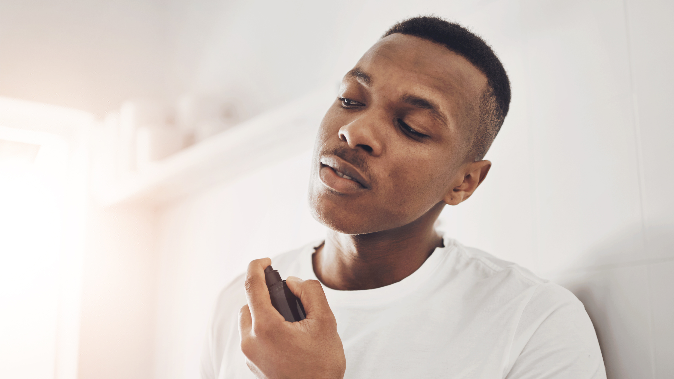 Man spraying cologne on his neck point